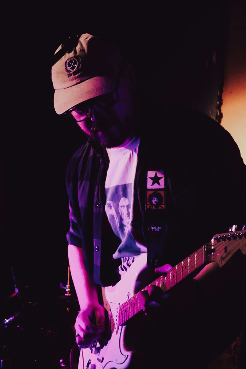 Sam playing guitar on stage during a performance
